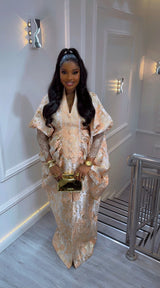 Amina Luxe Brocade Gown in beige with gold floral brocade, pleated waist, puff sleeves, and lace details for elegant occasions